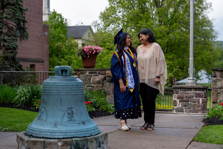 A student with her mother near the bell by the upper quad