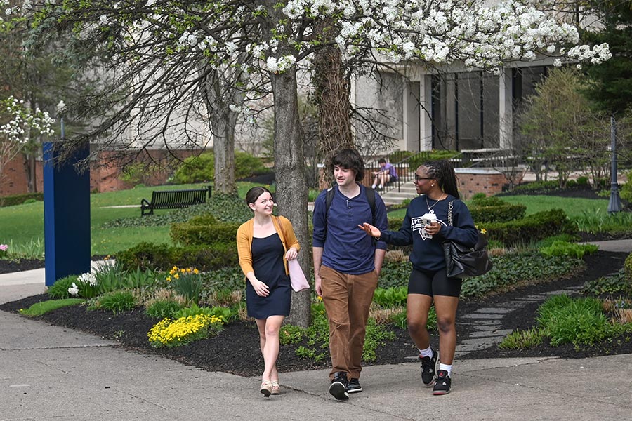 3 students walking in front of the academic center