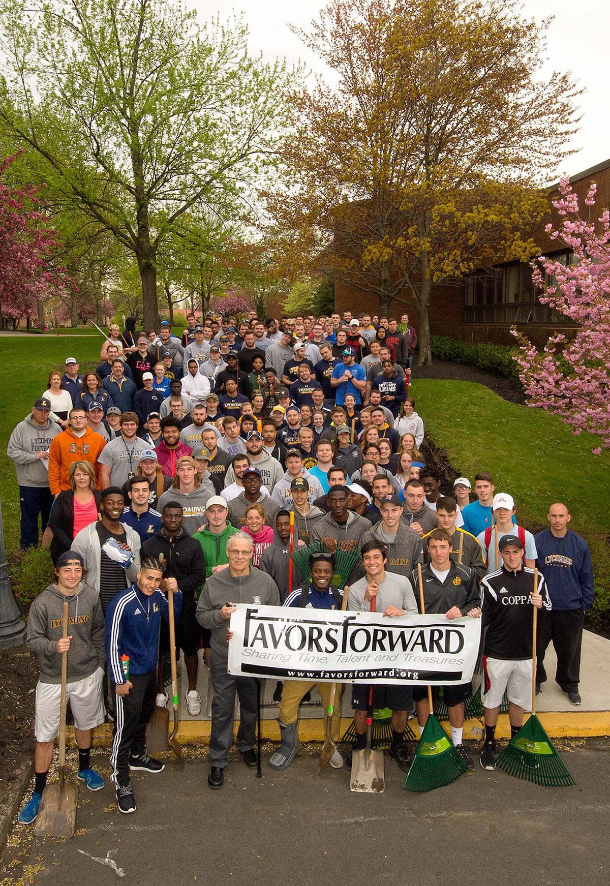 Lycoming athletes with Favors Forward banner