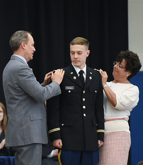 The parents of Jacob Fronko pin his bars during his commissioning.